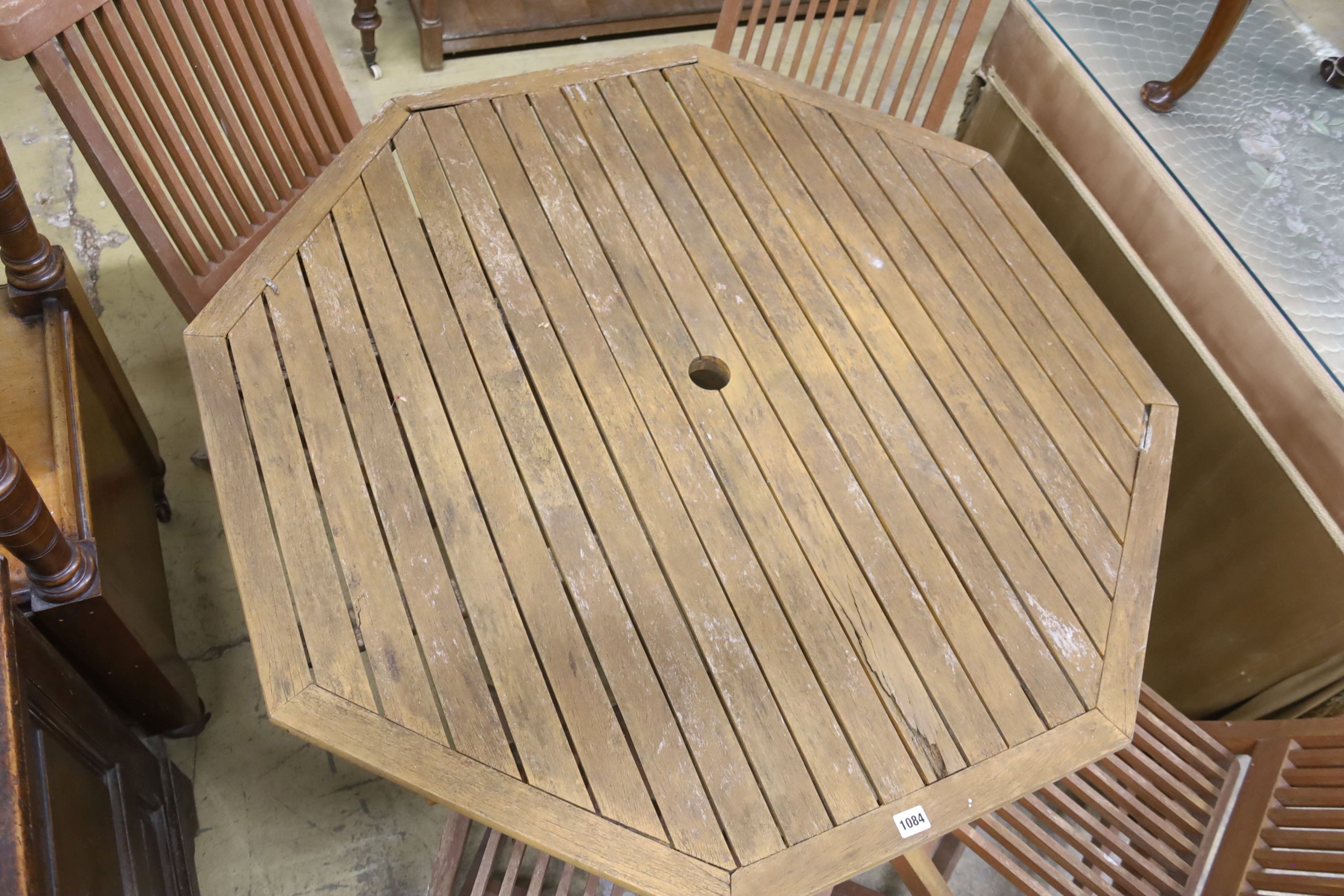 An octagonal teak garden table, width 111cm, height 69cm and four chairs